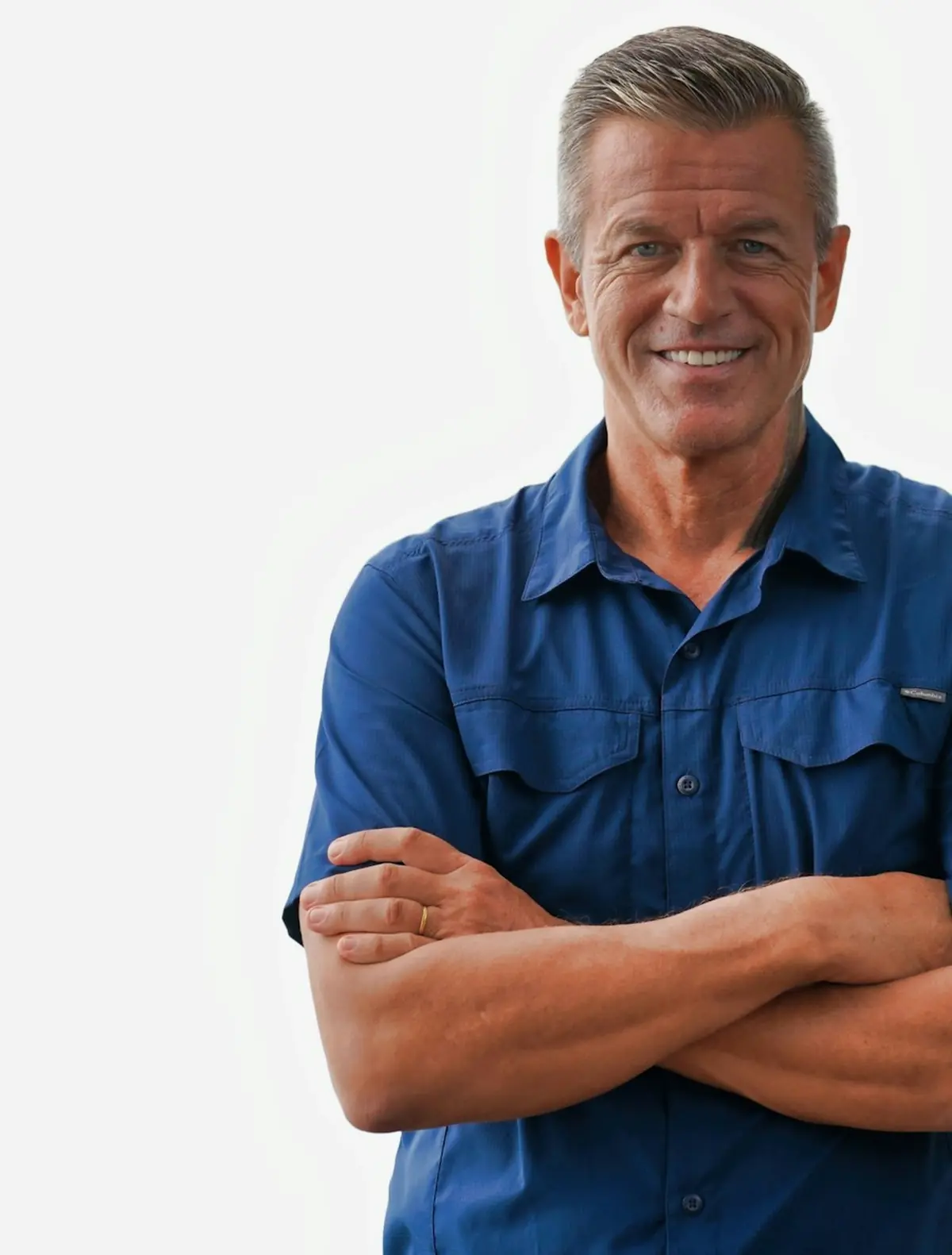 A smiling tradesman in a blue work shirt with his arms crossed